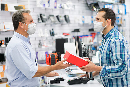 Latin American man wearing a facemask while shopping at a tech store during the COVID-19 pandemic