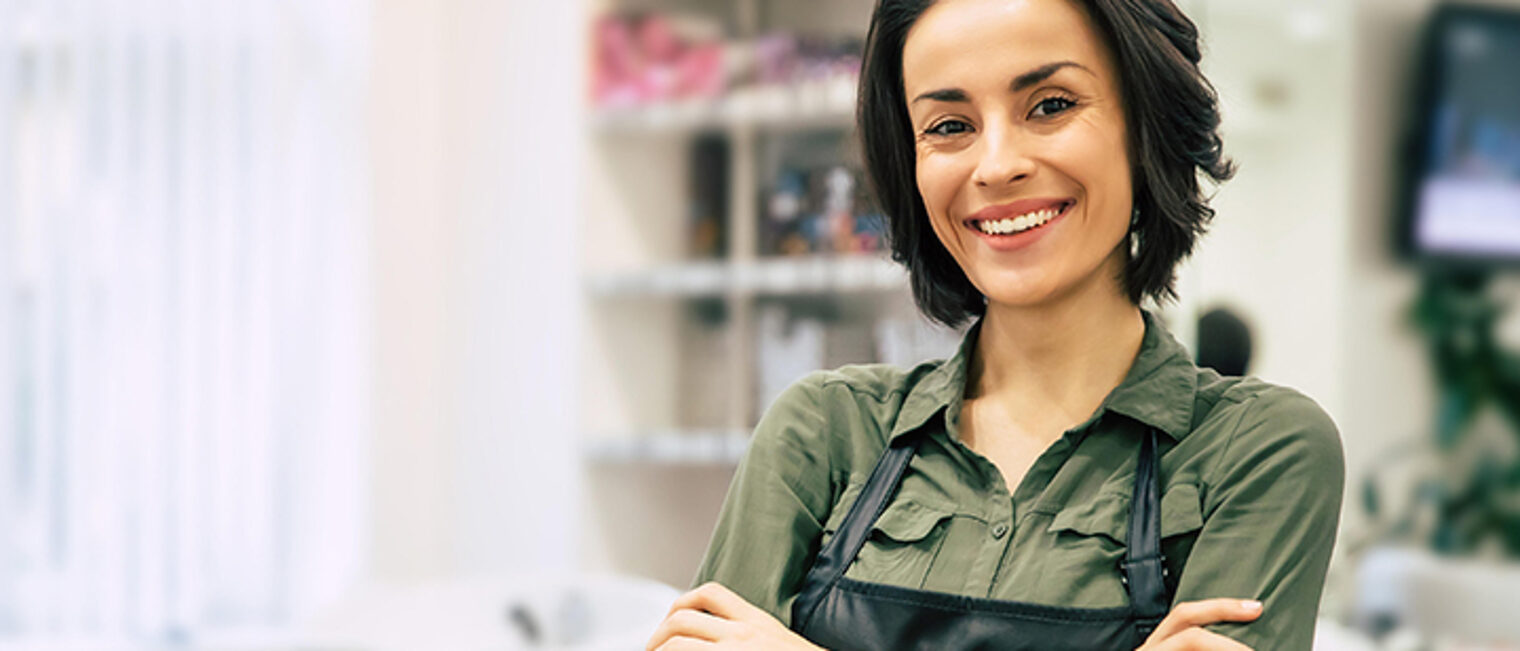 Portrait of a gorgeous young hairstylist standing with folded arms near her workplace in the salon.