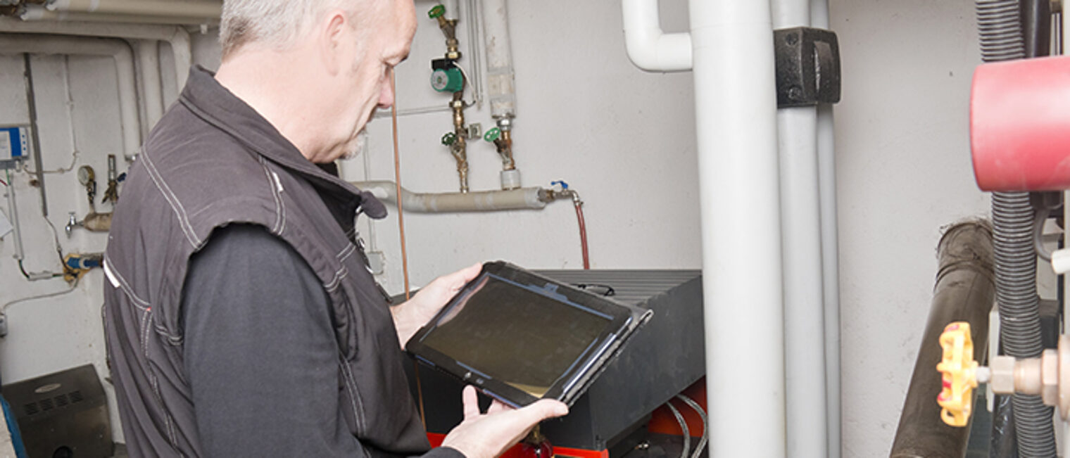 Technician checking with an instrument of measurement the emissions of an old oil heater,comply with air pollution limits.