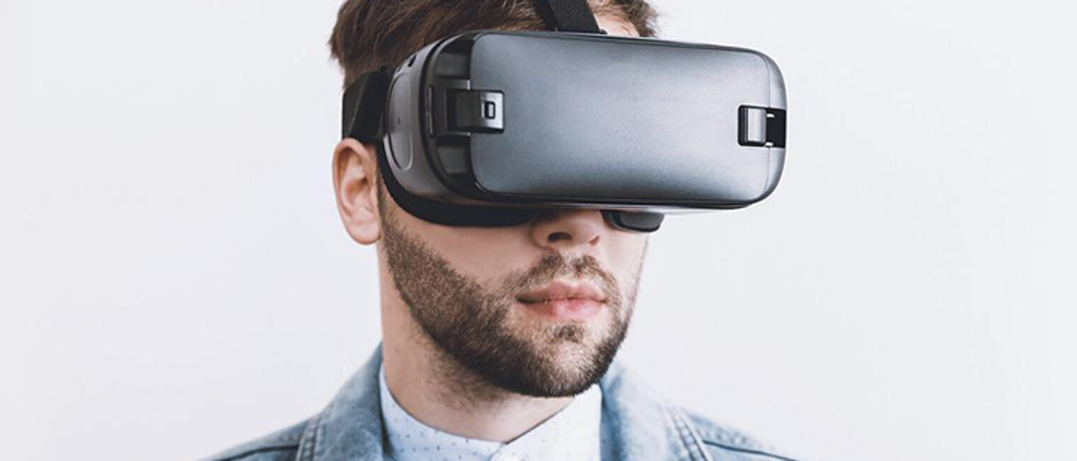 Junger Mann schaut durch eine VR-Brille.
