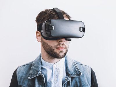 Junger Mann schaut durch eine VR-Brille.