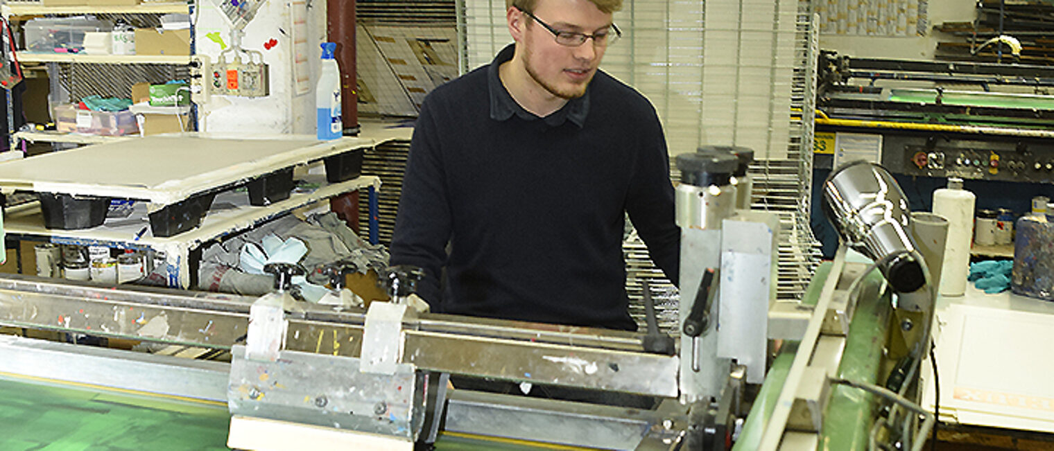 junger Mann arbeitet in der Siebdruckerei junger Mann arbeitet in der Siebdruckerei