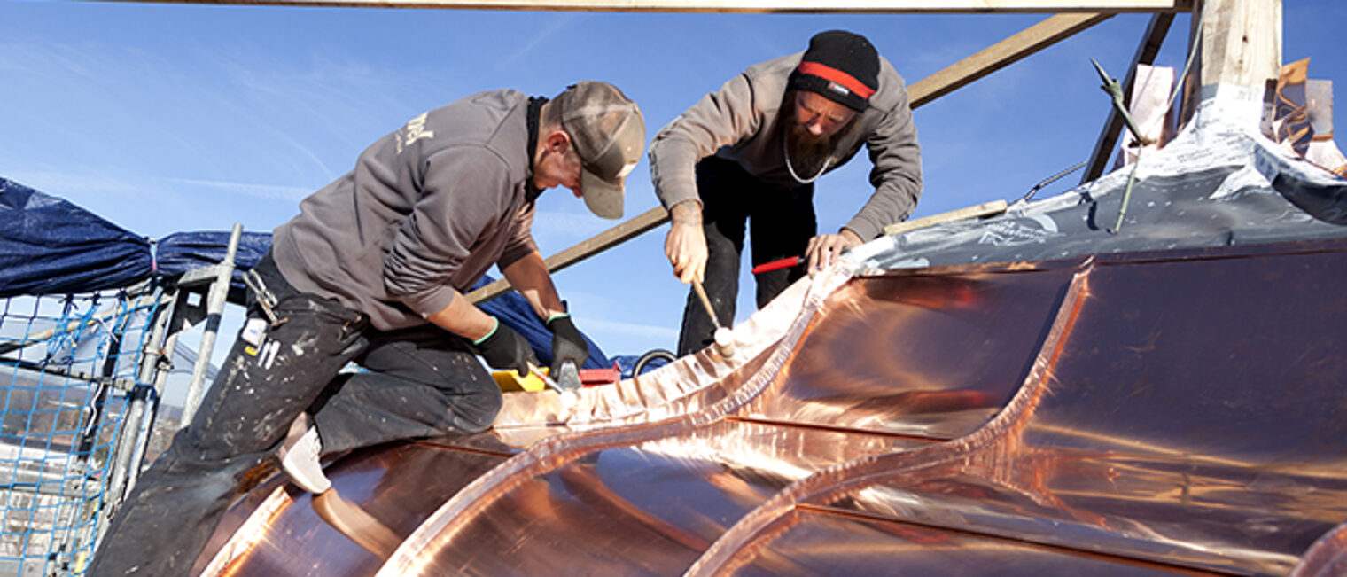 Zwei Klempner restaurieren ein Kupferdach