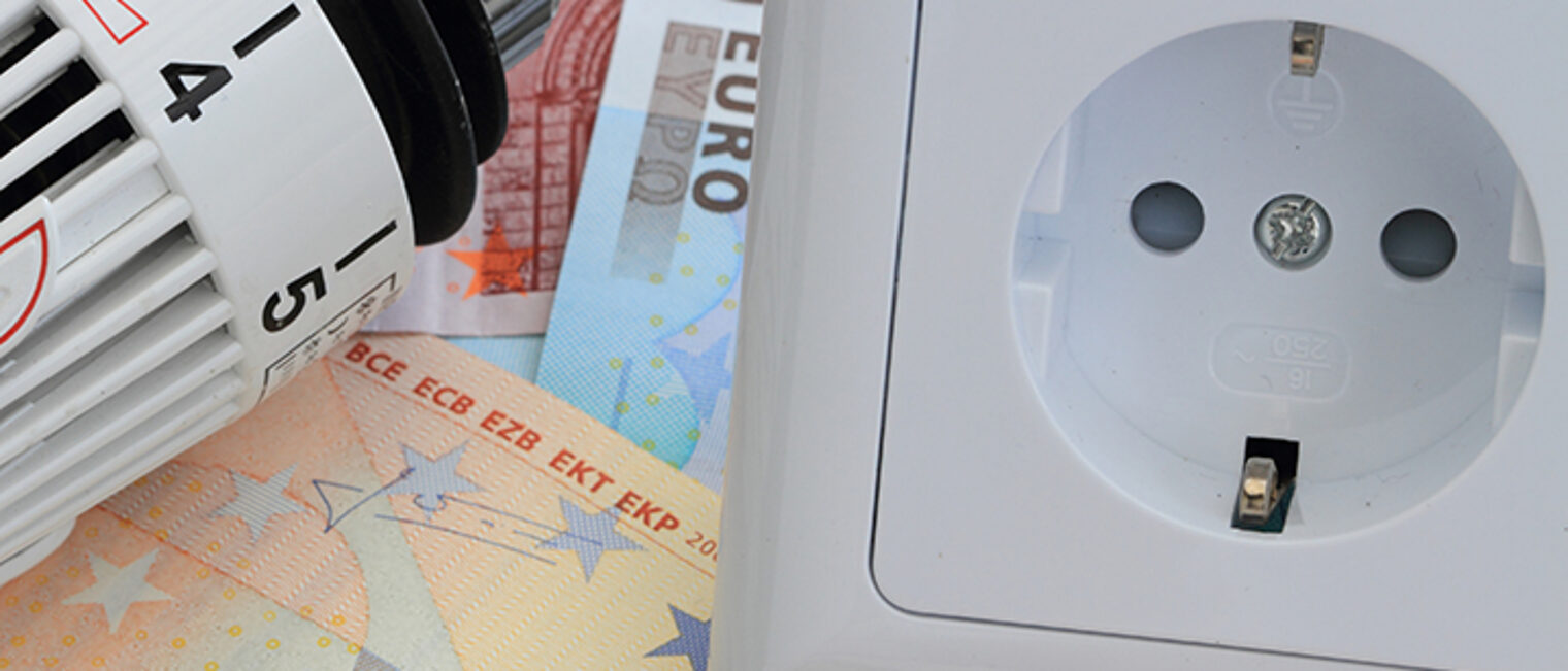 Thermostat und Steckdose liegen auf Euro-Scheinen.
