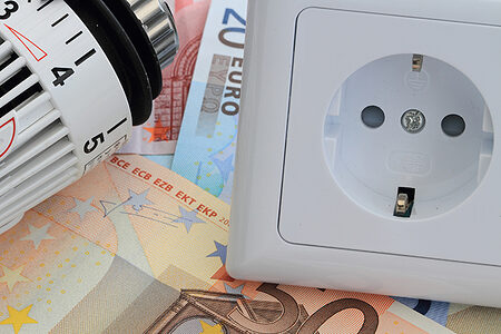 Thermostat und Steckdose liegen auf Euro-Scheinen.