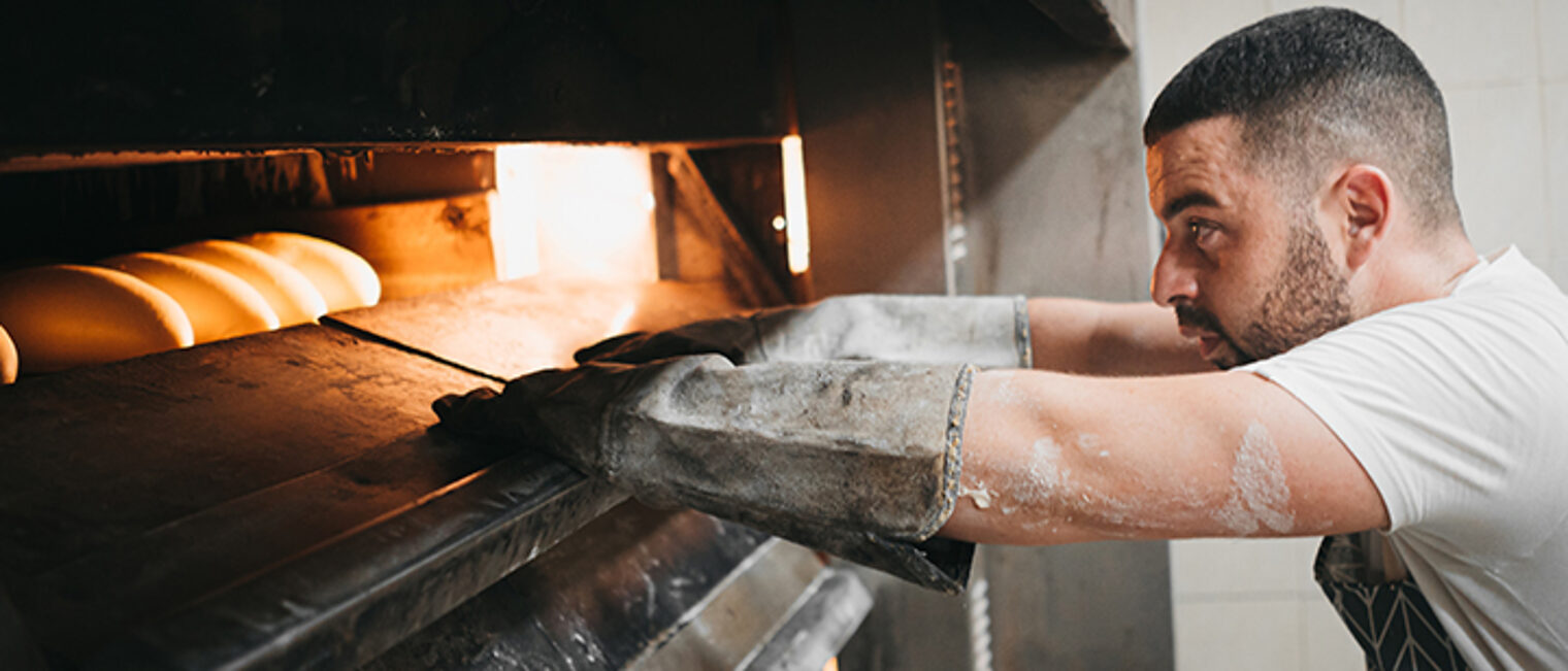 Bäcker holt Brot aus dem Backofen. Bäcker holt Brot aus dem Backofen.