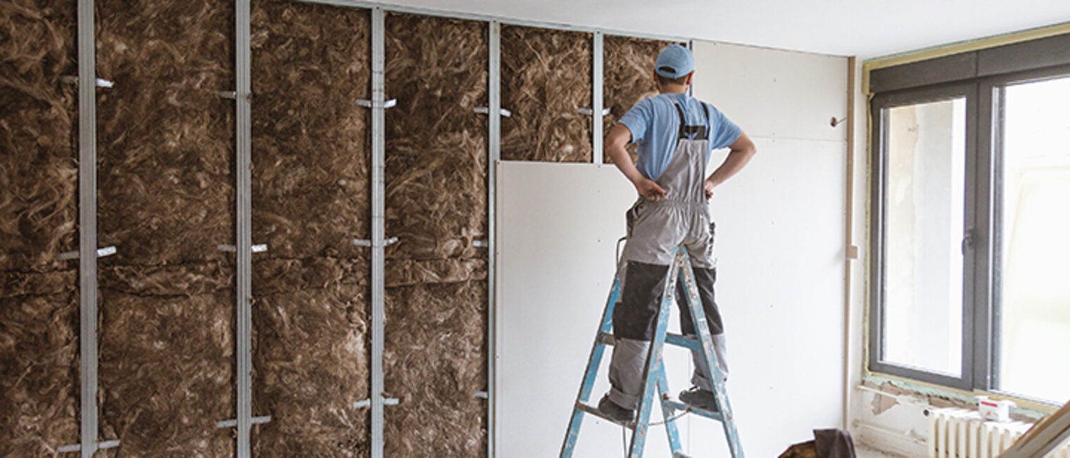 Construction site close up with workers making dry wall and implementing glass wool Earthwool-Acoustic.