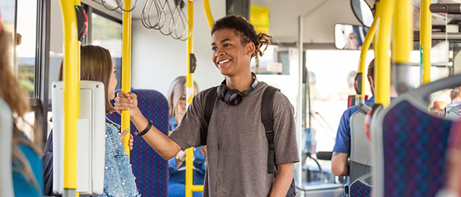 Ein Teenager spricht im Bus im Stehen mit einem Mädchen.