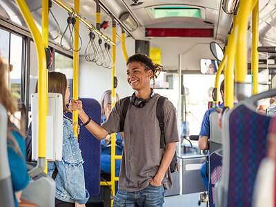 Ein Teenager spricht im Bus im Stehen mit einem Mädchen.