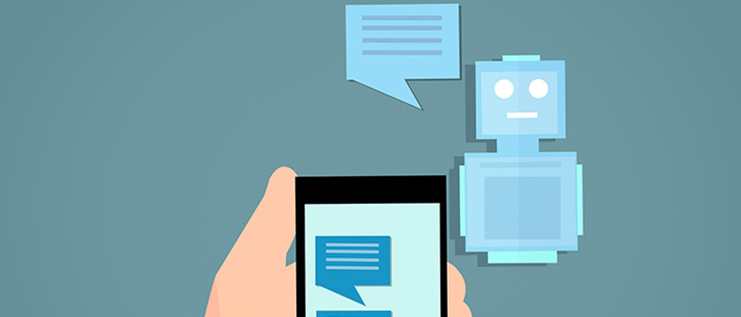 Grafik zeigt eine Hand mit Smartphone, auf dessen Bildschirm Sprechblasen abgebildet sind. Daneben ein kleiner Roboter mit einer Sprechblase. Grafik zeigt eine Hand mit Smartphone, auf dessen Bildschirm Sprechblasen abgebildet sind. Daneben ein kleiner Roboter mit einer Sprechblase.