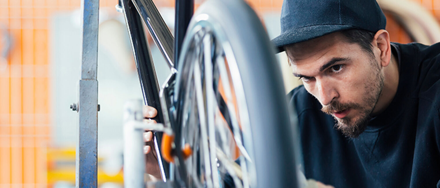 Zweiradmechaniker arbeitet in der Werkstatt an einem Fahrrad. Zweiradmechaniker arbeitet in der Werkstatt an einem Fahrrad.