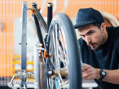 Zweiradmechaniker arbeitet in der Werkstatt an einem Fahrrad.
