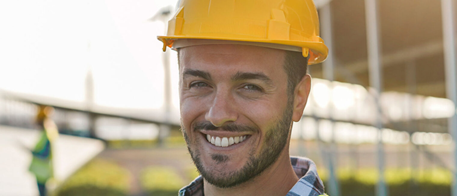 Porträt eines Mannes mit Schutzhelm und Warnweste auf einer Baustelle Porträt eines Mannes mit Schutzhelm und Warnweste auf einer Baustelle