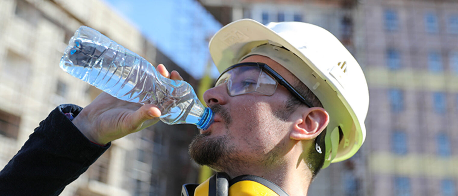 Bauhandwerker trinkt aus einer Wasserflasche.