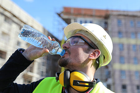 Bauhandwerker trinkt aus einer Wasserflasche.