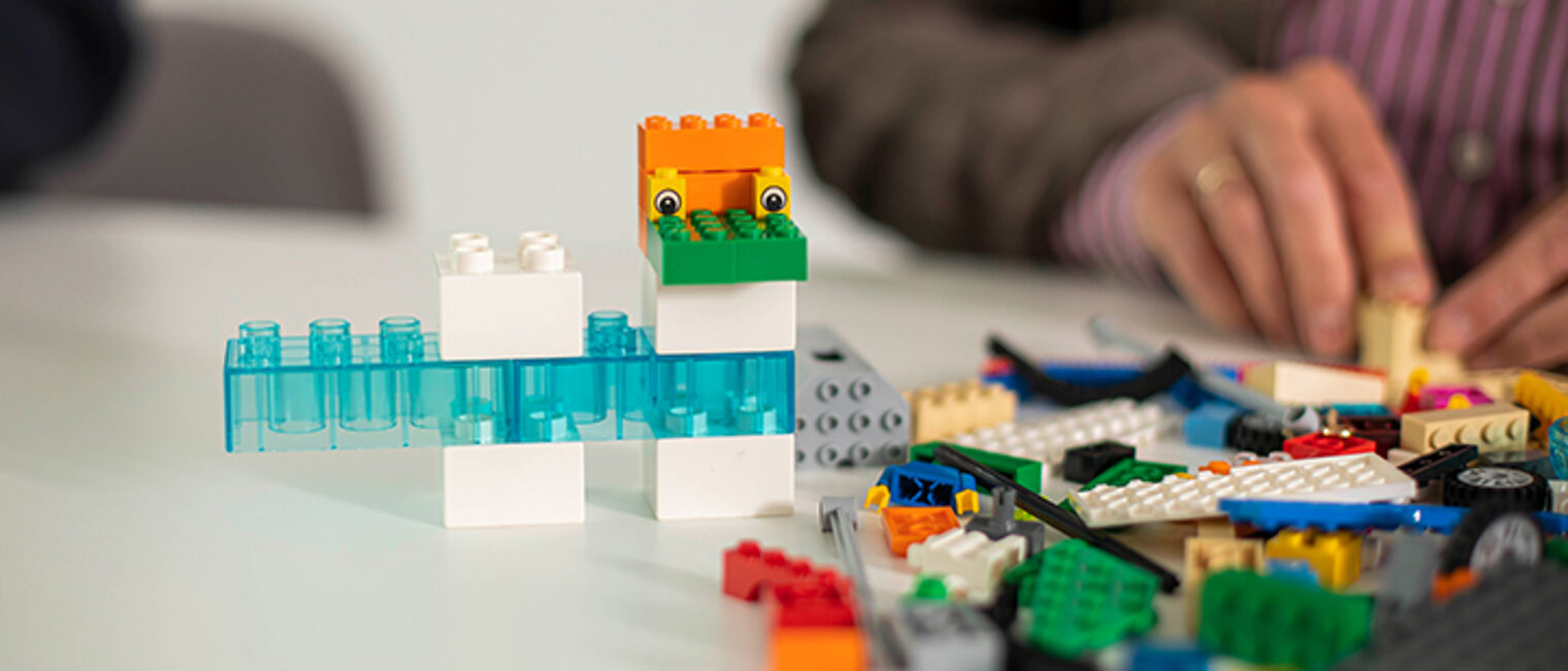 Erwachsener baut auf einem Tisch etwas mit Legosteinen. Erwachsener baut auf einem Tisch etwas mit Legosteinen.