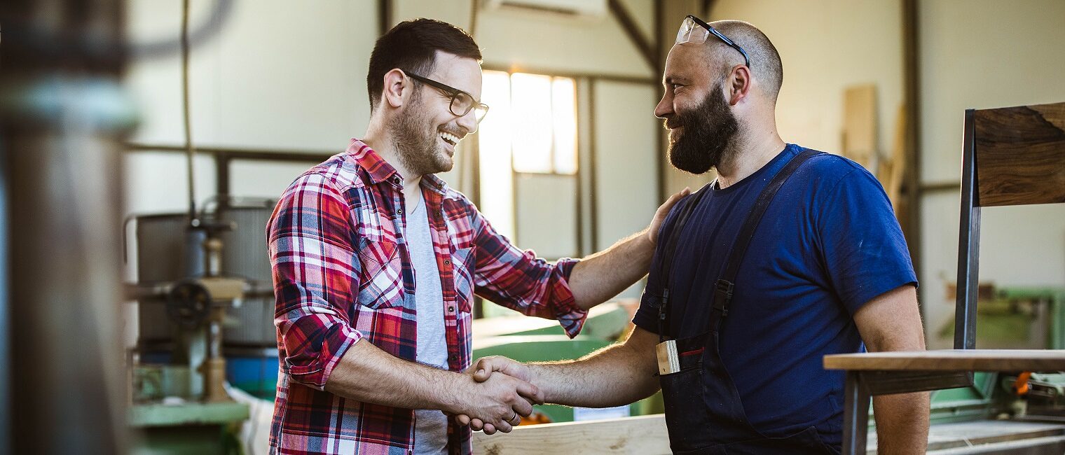 Happy manual worker and his customer came to an agreement in a workshop.