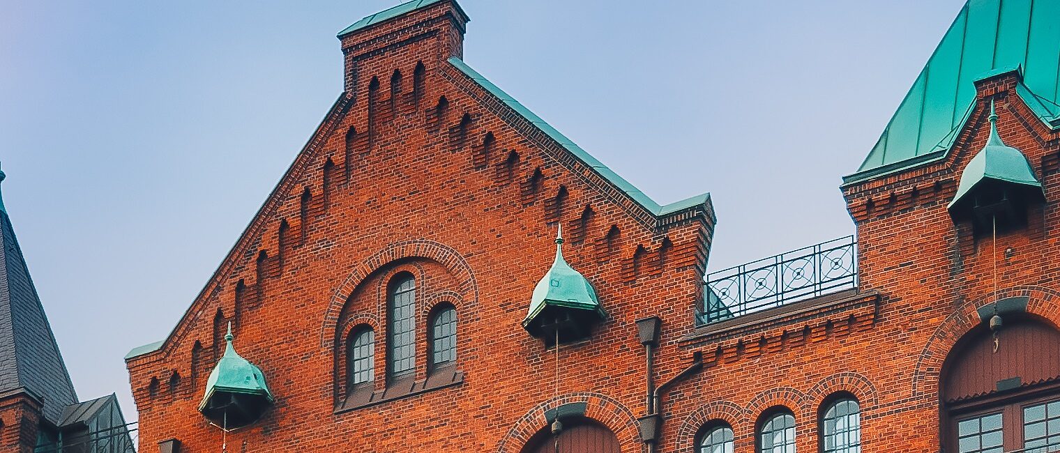 Arch bridge over alster canals with cobbled road in historical Speicherstadt of Hamburg, Germany, Europe. Scenic view of red brick building lit by golden sunset light.