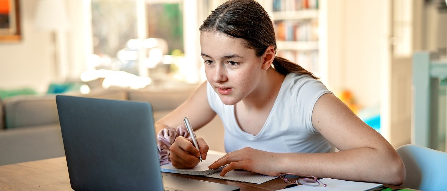 Teenager girl studying online at home looking at laptop at quarantine isolation period during pandemic. Home schooling. Social distancing. Online school test. Schlagwort(e): portable computer