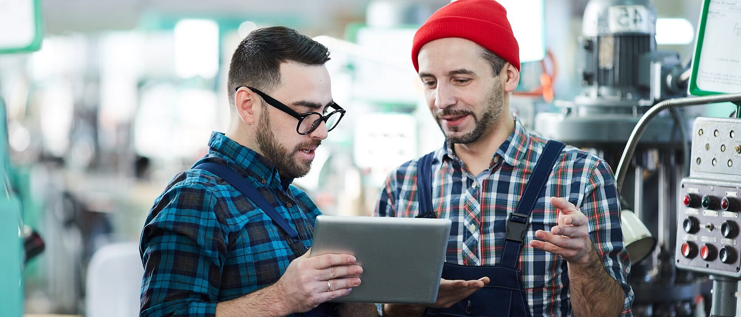 Waist up portrait of two factory workers using digital tablet in workshop