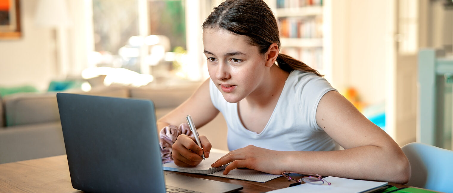 Teenager girl studying online at home looking at laptop at quarantine isolation period during pandemic. Home schooling. Social distancing. Online school test. Schlagwort(e): portable computer