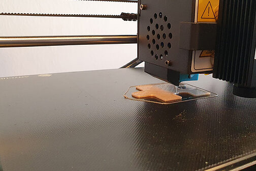3-D-Drucker druckt ein Holz-Puzzleteil.