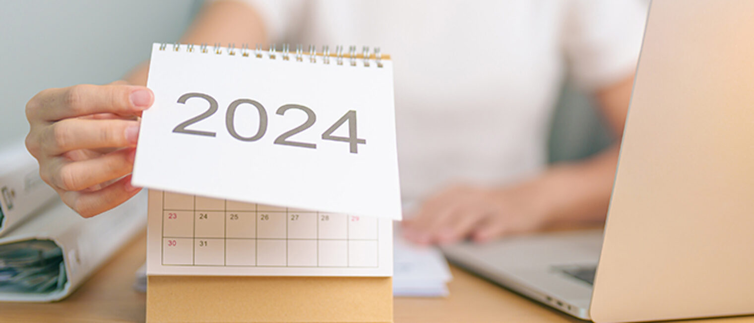 Frau blättert Tischkalender auf 2024 um. Frau blättert Tischkalender auf 2024 um.