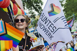 Frau mit Sonnenbrille und Regenbogenfahne bei der CSD-Parade