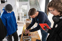 Schüler und Handwerker am Werktisch.