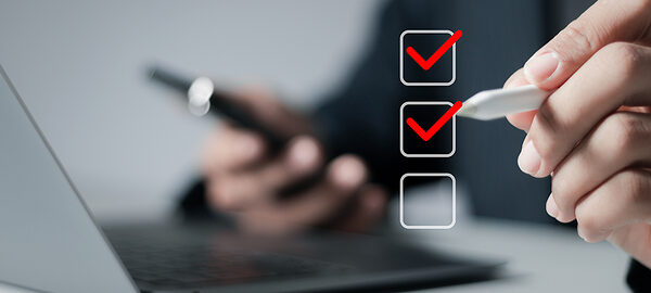 Mann füllt am Laptop Checkliste aus und setzt Häkchen.