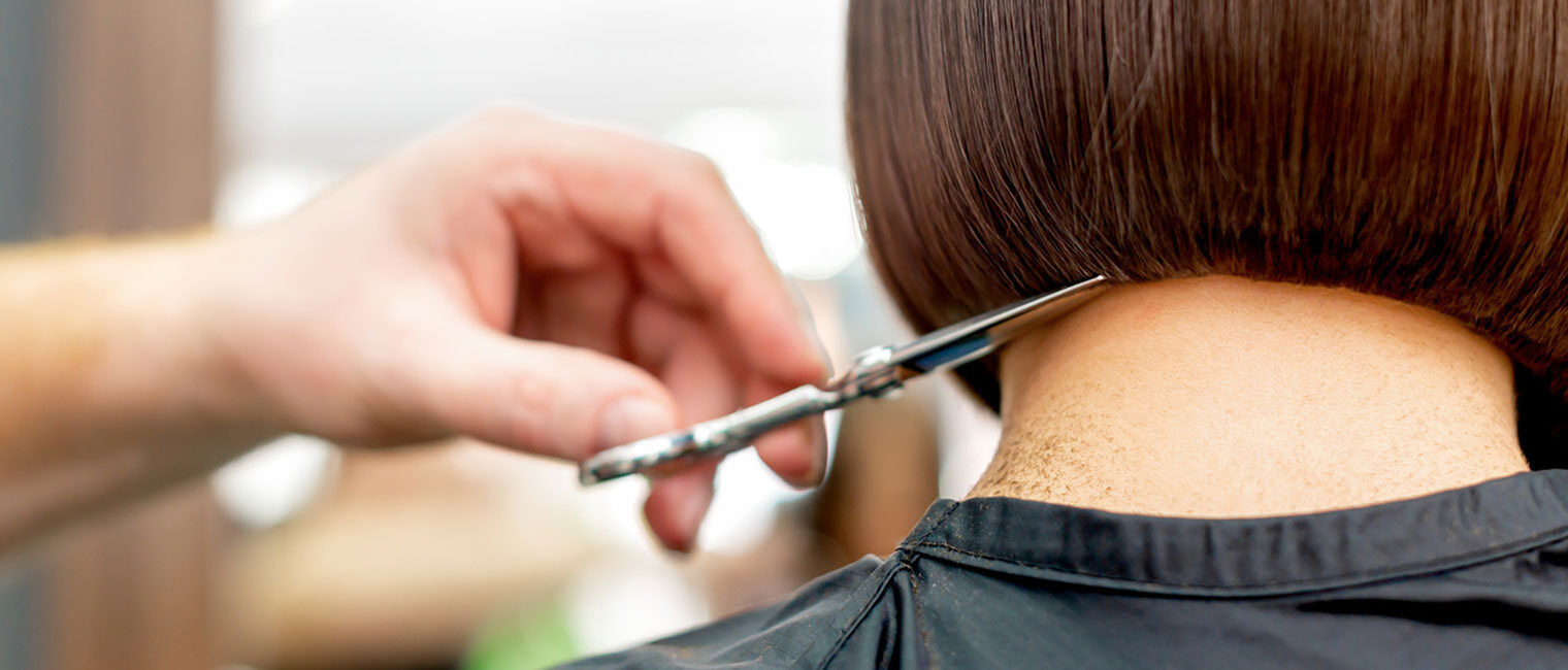 Friseur*in schneidet Haare einer Frau
