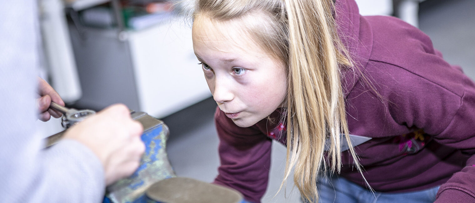 Mädchen prüft Werkstück an Schraubzwinge.