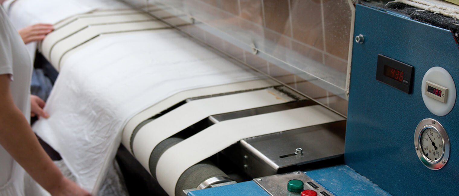 Trocken und Mangeln von weißer Wäsche an einer Maschine