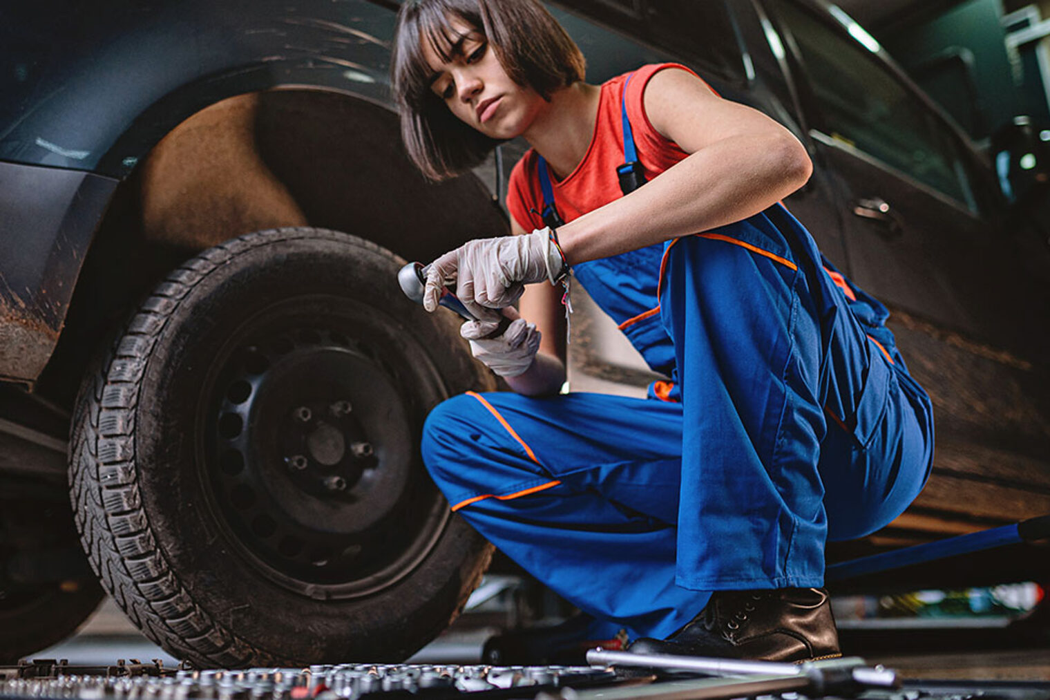 Automechanikerin wechselt in ihrer Reparaturwerkstatt einen Reifen an einem Auto
