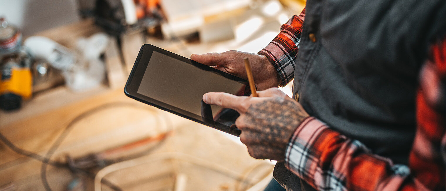 Handwerker in Werkstatt mit Tablet informiert sich