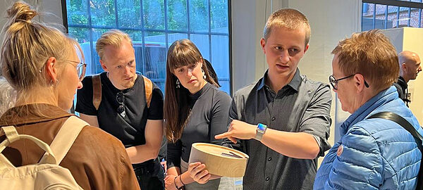 Junger Tischler erläutert Interessierten sein Werkstück, eine Schale.