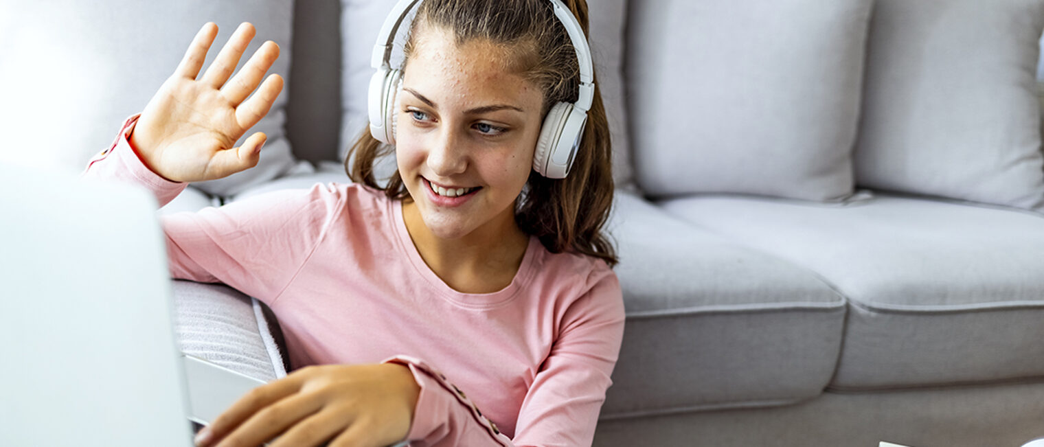 Mädchen mit Kopfhörern winkt beim Videocall