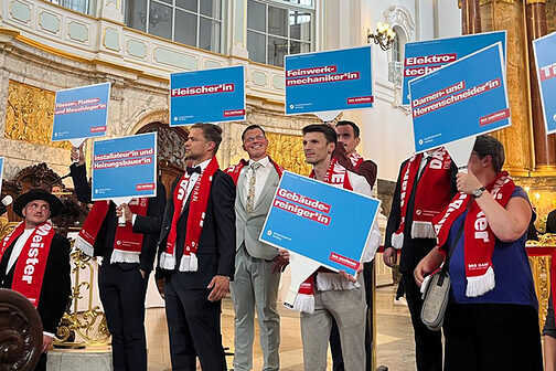 Jungmeisterinnen und -meister halten im Michel Schilder mit Gewerke-Bezeichnung hoch.