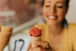 junge Frau reicht Eiswaffel über den Tresen