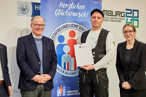 Zimmermann mit Urkunde und drei weitere Personen