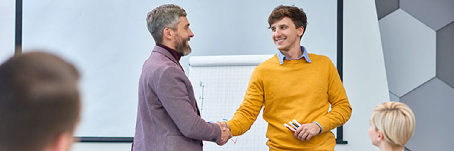 Portrait of young businessman presenting marketing report shaking hands with boss at the end of meeting